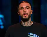 Malik Montana, z tatuażami na szyi, pokazuje język. Ile lat ma Malik Montana?