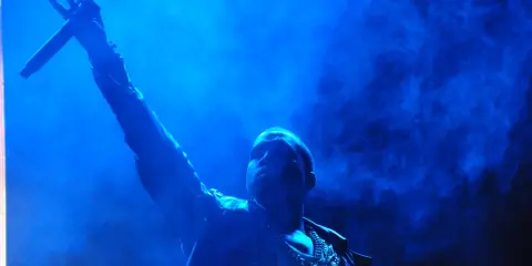 Kanye West z mikrofonem w dłoni, w niebieskiej poświacie. W tle dym, przypominający atmosferę z jego albumów.