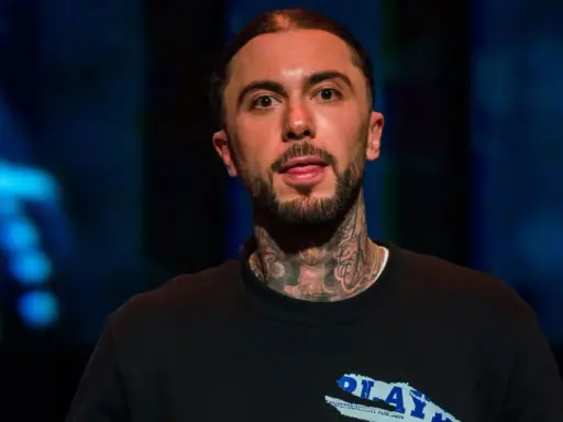 Malik Montana, z tatuażami na szyi, pokazuje język. Ile lat ma Malik Montana?