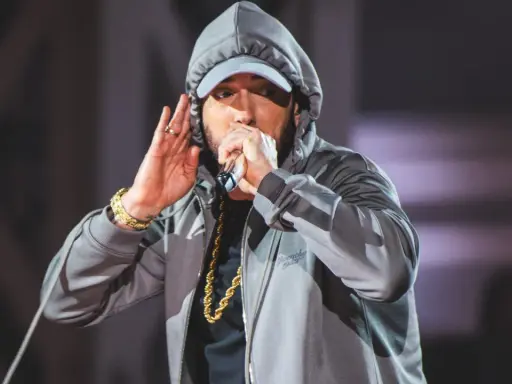 Eminem w kapturze i czapce, z mikrofonem w dłoni, jakby szykował kolejny eminem diss. Złoty łańcuch błyszczy.