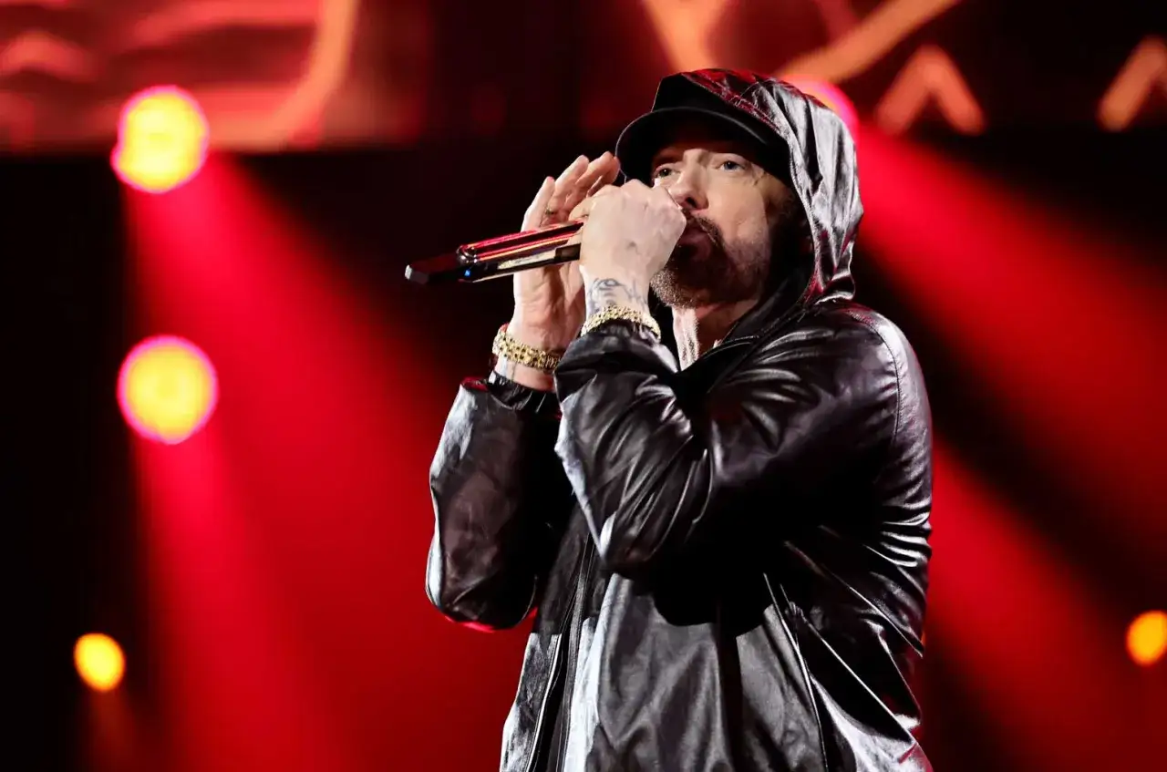 Eminem, raper znany z tego, że skąd pochodzi jego muzyka, występuje na scenie w skórzanej kurtce z kapturem.