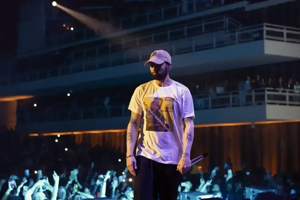 Eminem na scenie, w białej koszulce z nadrukiem, przed tłumem fanów. Czy to koncert w Polsce?